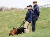 side shot ofZara Phillips in blue MUSTO jacket and polo cap on hillside  with boxer and labrador with unknown older male
