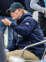 tight side shot of Zara Phillips eating a pizza wearing polo cap and blue MUSTO jacket