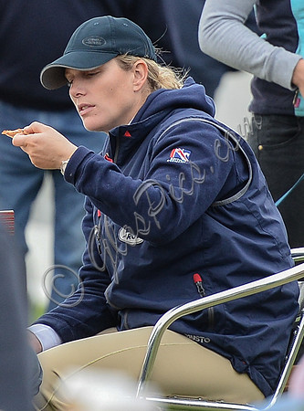 tight side shot of Zara Phillips eating a pizza wearing polo cap and blue MUSTO jacket