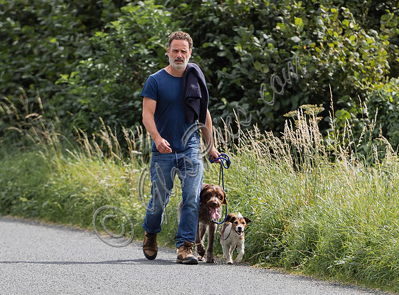 Andrew Lincoln dressed casually walking his two dogs