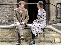 male and female sat on wall of Village Hall in period dress