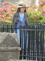 Georgia Brinkworth (Phyll) in the school yard behind railings wearing straw hat