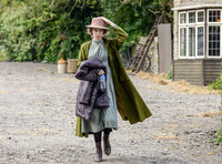 Emma Curtis as Marge holding her hat wearing lime green duster coat