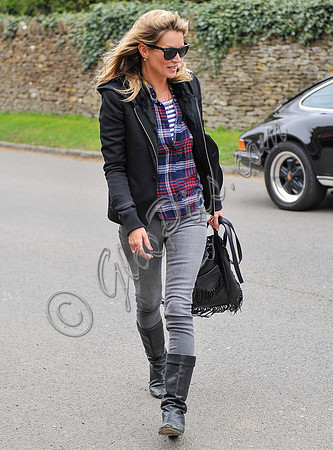 wearing trademark grey skinny jeans, black boots and a pair of Ray-Ban Wayfarer sunglasses, striped 'T', plaid shirt, hoodie with tailored jacket,  carrying Genevieve Jones fringed bag