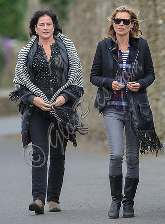 wearing trademark grey skinny jeans, black boots and a pair of Ray-Ban Wayfarer sunglasses, striped 'T', plaid shirt, hoodie with tailored jacket, carrying Genevieve Jones fringed bag, with unidentif