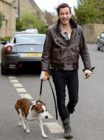 Jamie Hince wearing black skinny jeans, scruffy boots and brown bomber style leather jacket, with dog  "Archie" on lead.