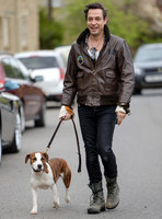 Jamie Hince wearing black skinny jeans, scruffy boots and brown bomber style leather jacket, with dog  "Archie" on lead.