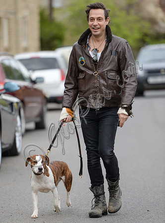 Jamie Hince wearing black skinny jeans, scruffy boots and brown bomber style leather jacket, with dog  "Archie" on lead.