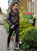Jamie Hince wearing black skinny jeans, scruffy boots and brown bomber style leather jacket, with dog  "Archie" on lead.