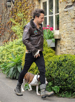 Jamie Hince wearing black skinny jeans, scruffy boots and brown bomber style leather jacket, with dog  "Archie" on lead.