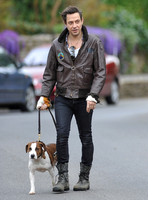 Jamie Hince wearing black skinny jeans, scruffy boots and brown bomber style leather jacket, with dog  "Archie" on lead.