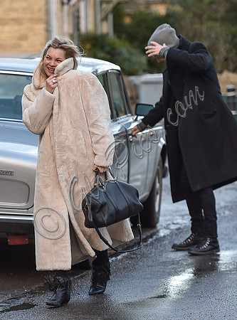 Kate Moss in calf length faux fur coat giggling with Jefferson Hack in background.
