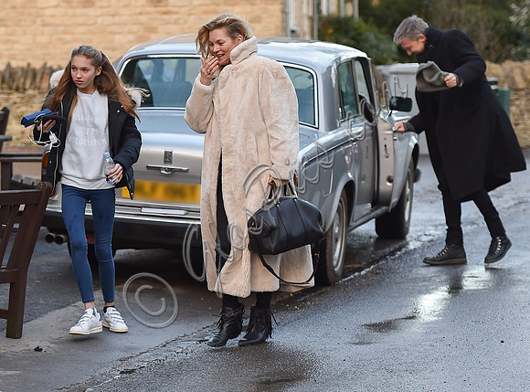 Kate Moss in calf length faux fur coat giggling with Jefferson Hack in background.