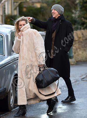 Kate Moss in calf length faux fur coat giggling with Jefferson Hack in background.