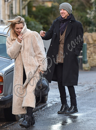 Kate Moss in calf length faux fur coat giggling with Jefferson Hack in background.