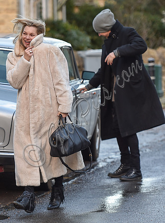 Kate Moss in calf length faux fur coat giggling with Jefferson Hack in background.