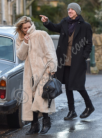 Kate Moss in calf length faux fur coat giggling with Jefferson Hack in background.