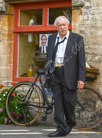 Michael Gambon in diseray, outside Mollisons delicatessen with bicycle in background