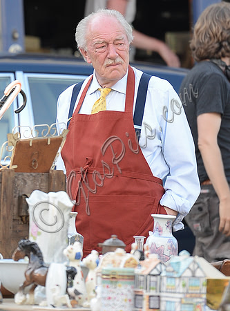 Sir Michael Gambon as Howard Mollison wearing blue pyjamas and monogrammed slippers