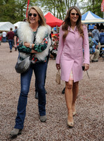 Georgia Daventry wearing jeans, brightly coloured blouse and fluffy gilet with Elizabeth Hurley in a pink coat both wearing sunglasses walking towards camera.