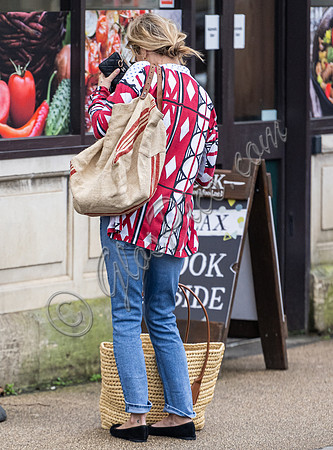 Kate Moss with loose hair knot, wearing denims, multi coloured top and ballet pumps