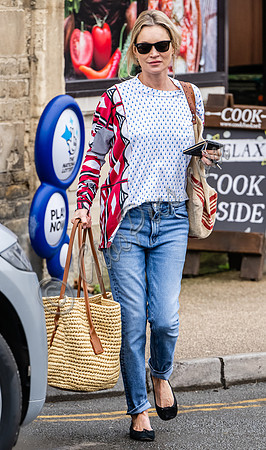 Kate Moss with loose hair knot, wearing denims, multi coloured top and ballet pumps