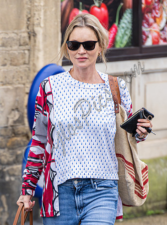 Kate Moss with loose hair knot, wearing denims, multi coloured top and ballet pumps