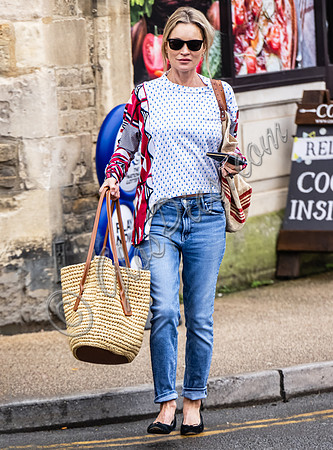 Kate Moss with loose hair knot, wearing denims, multi coloured top and ballet pumps