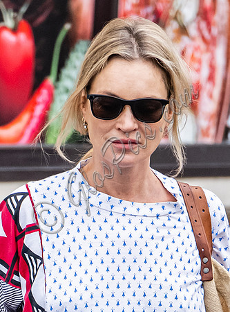Kate Moss with loose hair knot, wearing denims, multi coloured top and ballet pumps
