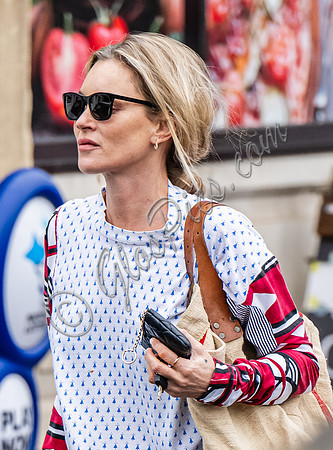 Kate Moss with loose hair knot, wearing denims, multi coloured top and ballet pumps