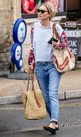 Kate Moss with loose hair knot, wearing denims, multi coloured top and ballet pumps
