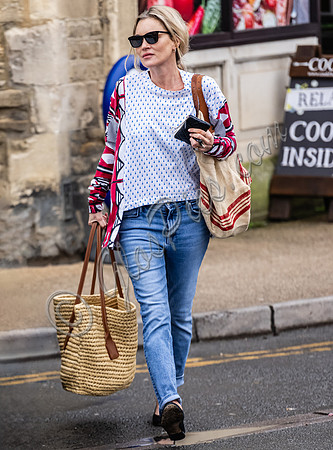 Kate Moss with loose hair knot, wearing denims, multi coloured top and ballet pumps