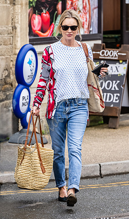 Kate Moss with loose hair knot, wearing denims, multi coloured top and ballet pumps