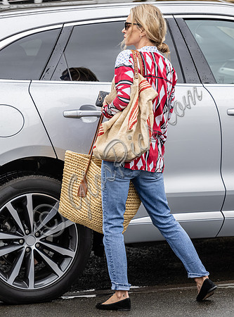 Kate Moss with loose hair knot, wearing denims, multi coloured top and ballet pumps