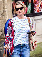 Kate Moss with loose hair knot, wearing denims, multi coloured top and ballet pumps