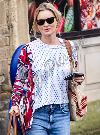 Kate Moss with loose hair knot, wearing denims, multi coloured top and ballet pumps
