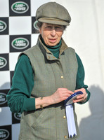 Princess Anne holding rosette wearing matching tweed hat and body warmer