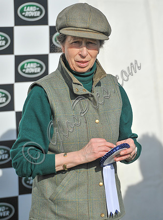 Princess Anne holding rosette wearing matching tweed hat and body warmer