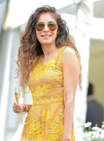 Attractive female wearing RayBan aviator sunglasses and a yellow lace dress holding a champagne flute