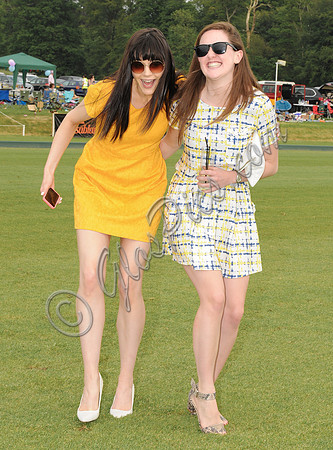Treading divots at polo match, Lilah Parsons wearing bright yellow mini dress with another female