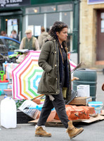 Karla Crome with dreadlocks wearing parka, grey trousers and workboots in a market scene from "Apocalypse Slough"