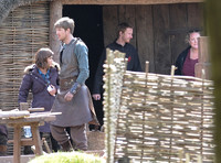 Jenna Coleman with cast member in costume, and crew on the Doctor Who set.