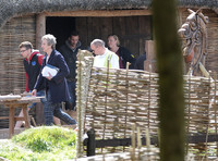 Peter Capaldi with crew members on the Doctor Who set with large wooden horse far right of image