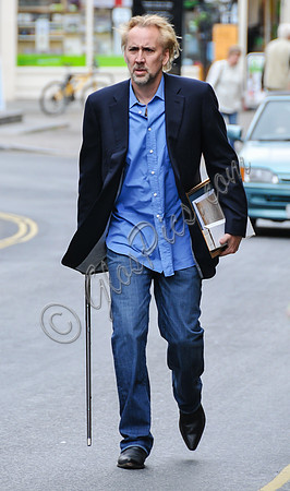 Blonde and bearded, Nicolas Cage with silver tipped walking cane