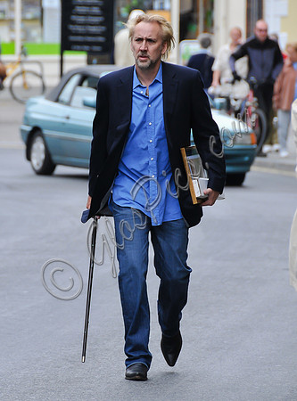 Blonde and bearded, Nicolas Cage with silver tipped walking cane