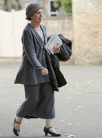 Penelope Wilton (Isobel Crawley) wearing grey suit and matching hat wearing Mary Jane button shoes and carrying a coat over arm.