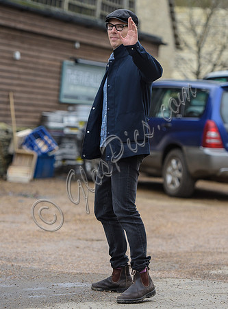 Benedict Cumberbatch wearing denim shirt, flat cap and glasses