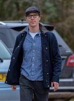 Benedict Cumberbatch wearing denim shirt, flat cap and glasses