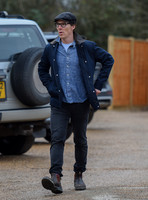 Benedict Cumberbatch wearing denim shirt, flat cap and glasses