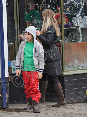 Kal-El Coppola Cage leaving jewellery shop with middle aged woman in Glastonbury, he is wearing Ralph Lauren hoodie, green T shirt, red trousers and heavy work style boots